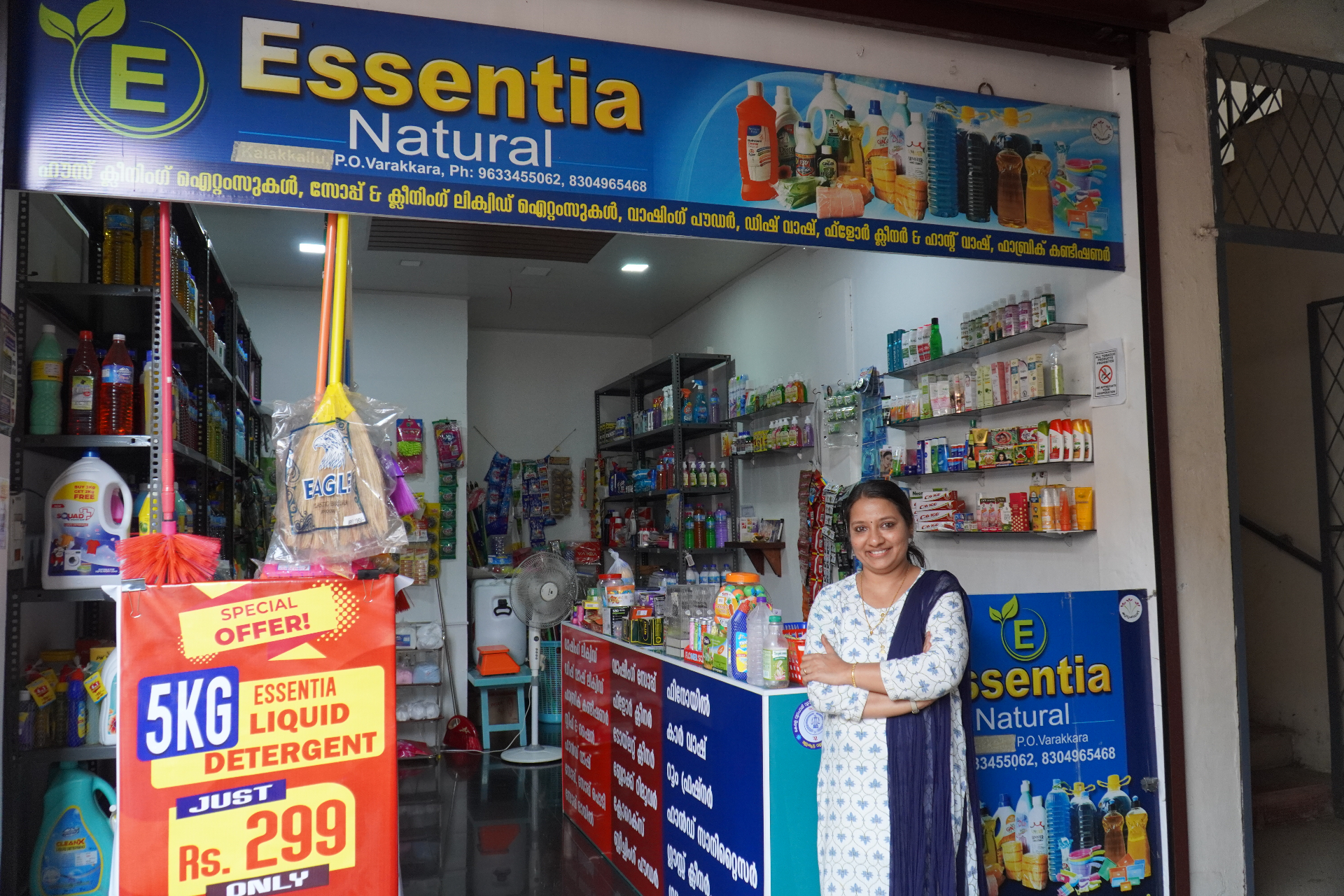 A woman shopkeeper standing at the front of Essentia Natural, her cleaning products shop in Varakkara, Kerala.